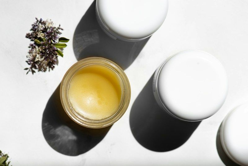 Pot de baume doré ouvert, vu de dessus, sur fond blanc