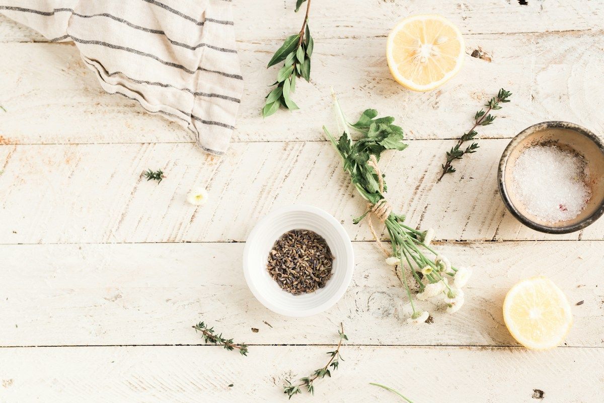 Plantes séchées, gros sel et citron posés sur une table en bois clair
